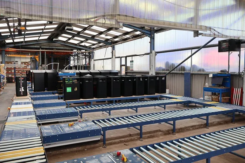 Multiple roller conveyor lines transporting street furniture litter bins through a manufacturing facility