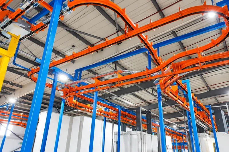 Curved overhead conveyor track within the manufacturing facility