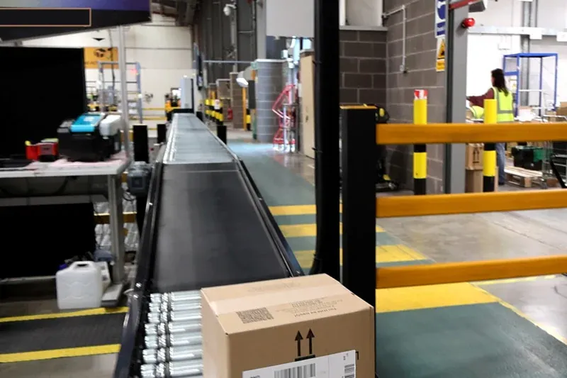 Long lineshaft roller conveyor installation transporting cartons through a distribution facility