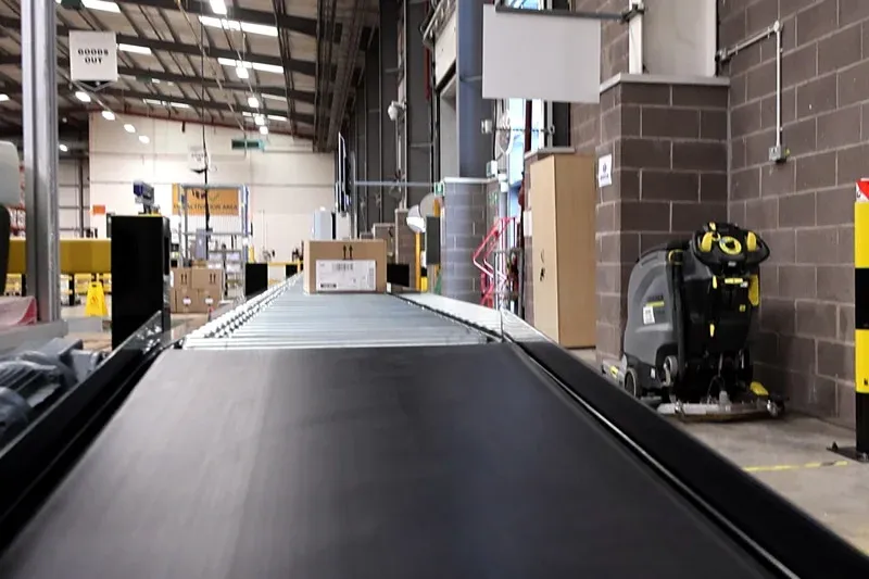 Integrated belt conveyor section connected to a lineshaft roller conveyor for carton handling