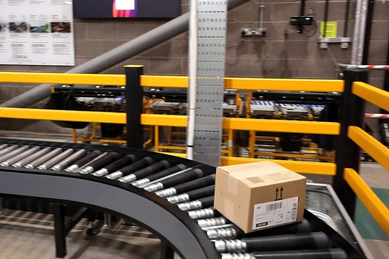 Conveyor system combining belt and roller conveyor sections within a warehouse